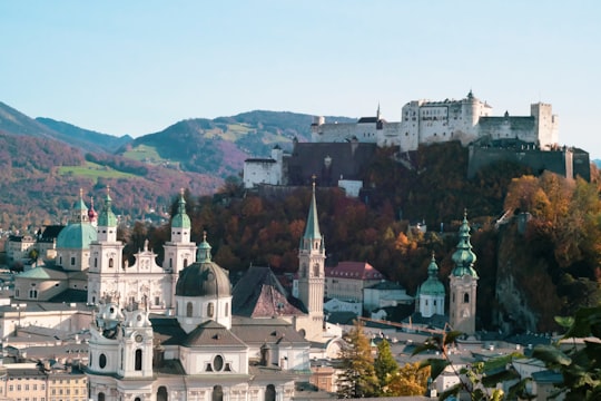 white and brown concrete building near green trees during daytime in Hohensalzburg Castle Austria