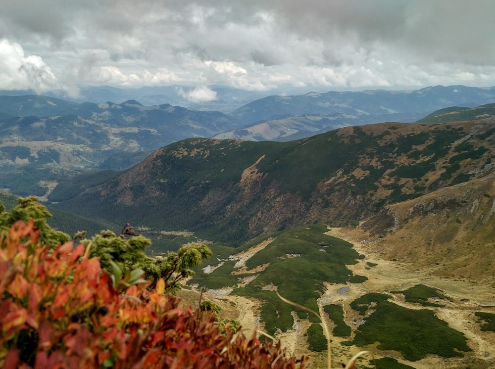 montañas verdes y marrones bajo nubes blancas durante el día