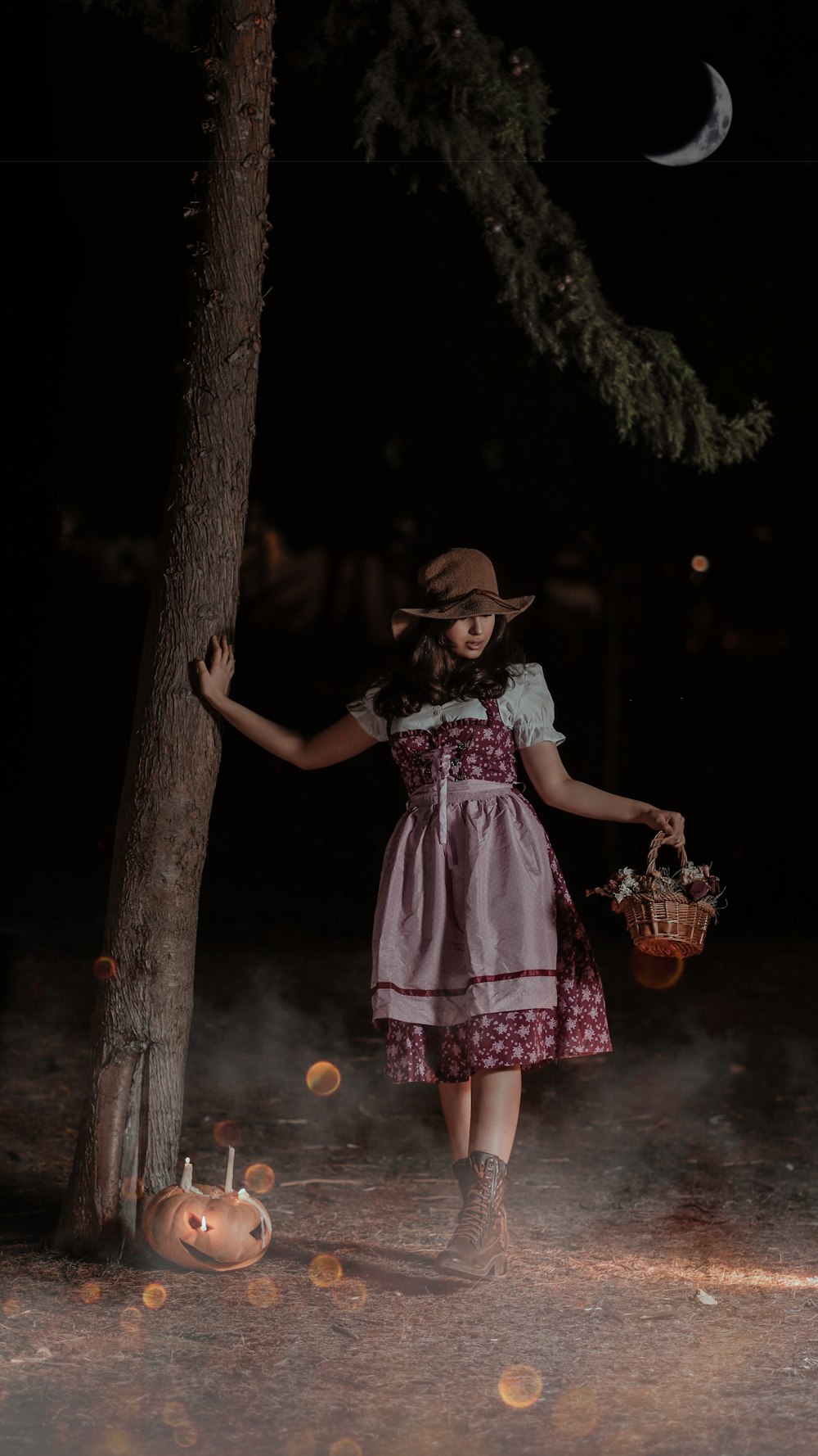 Mädchen in weiß-rotem Blumenkleid neben Baum