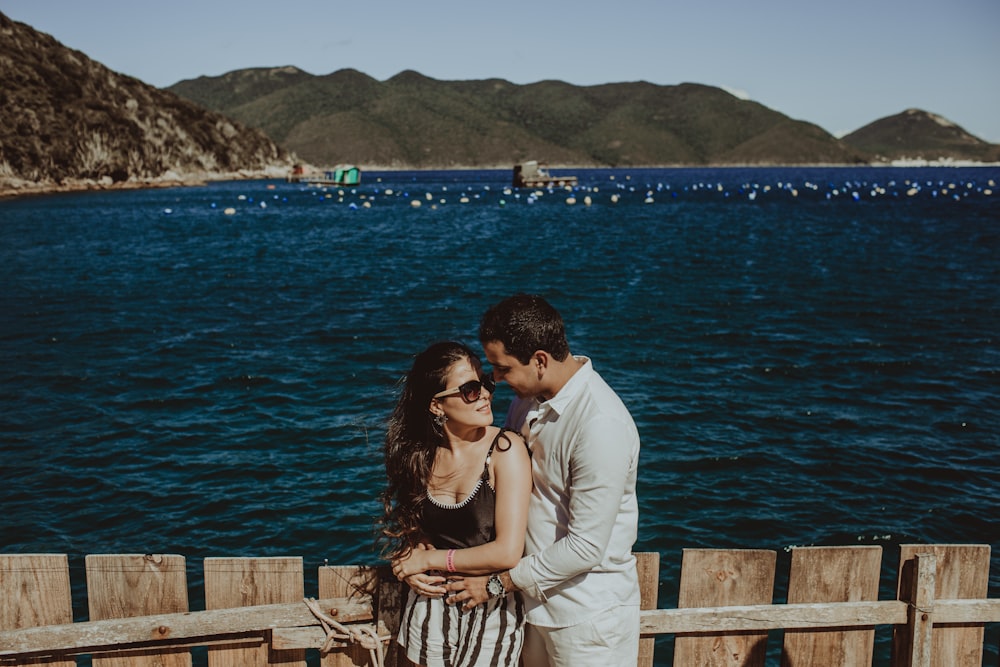 a man and woman standing next to each other near a body of water