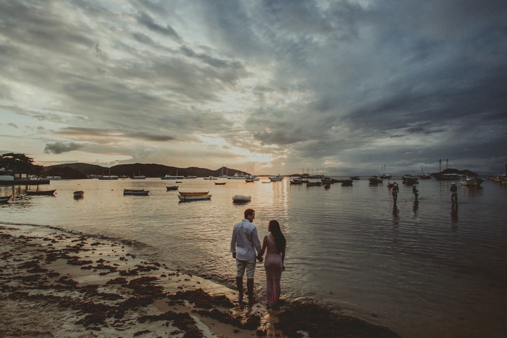 man and woman walking on beach during daytime