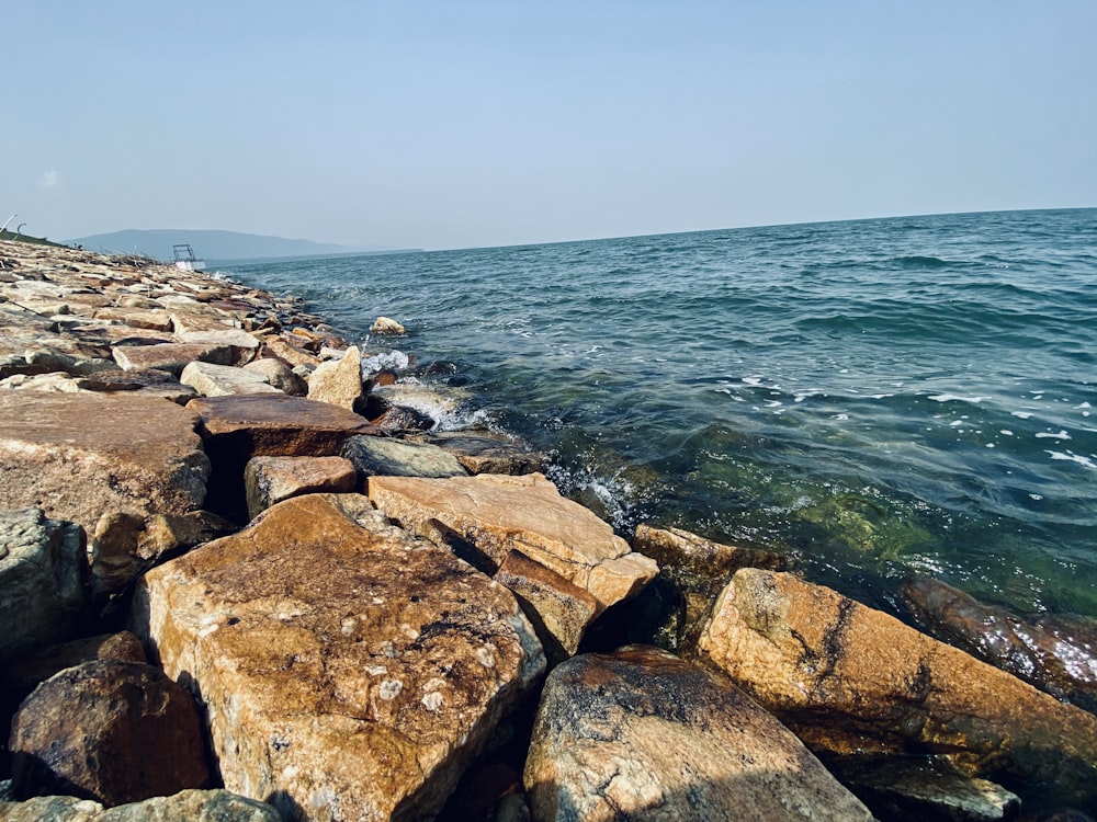a rocky shore line with a body of water in the background