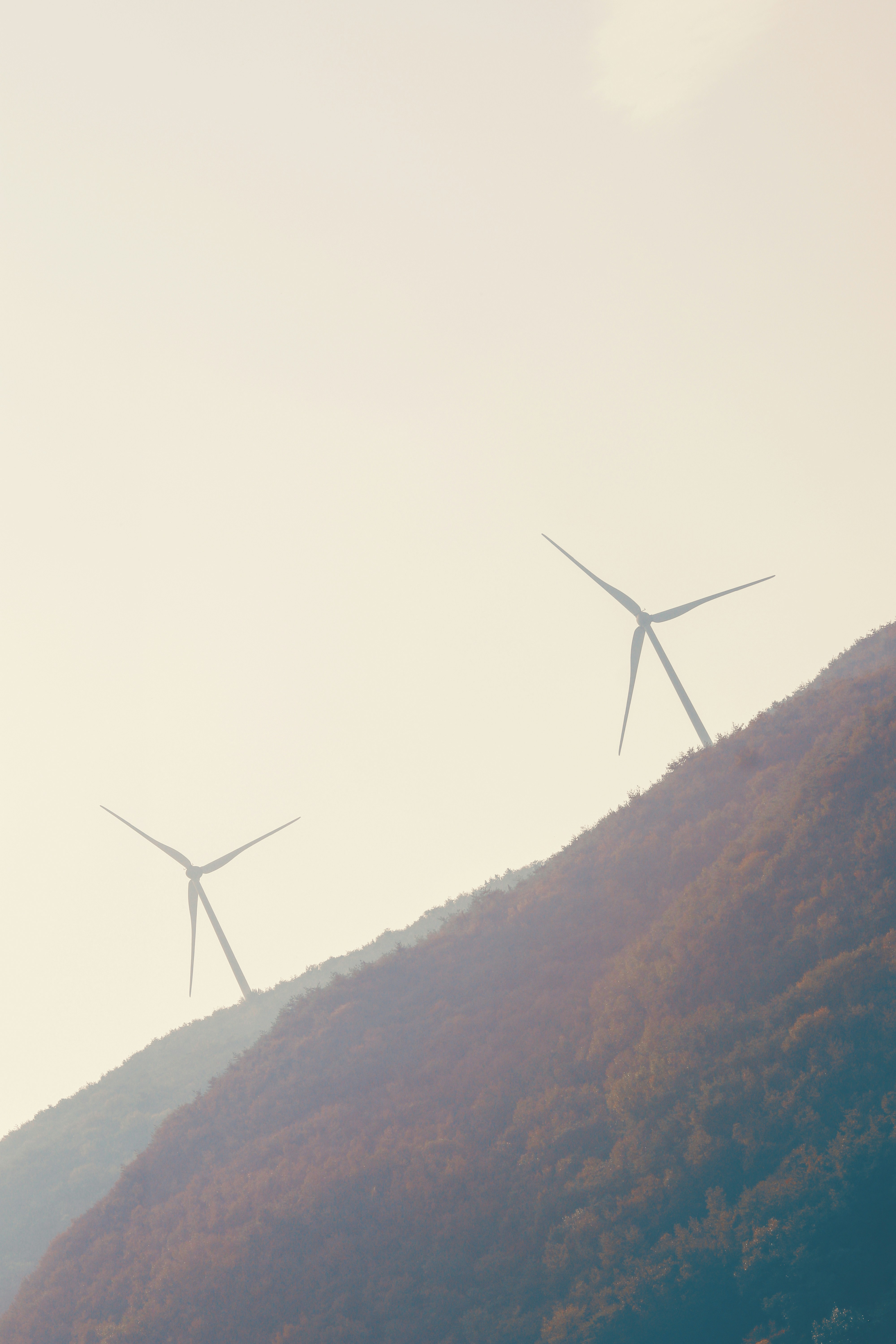 white wind turbine on brown and green mountain