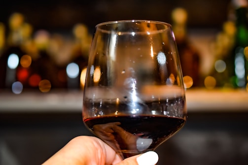 Close-up of a sommelier pouring red wine into a glass with a warm background.