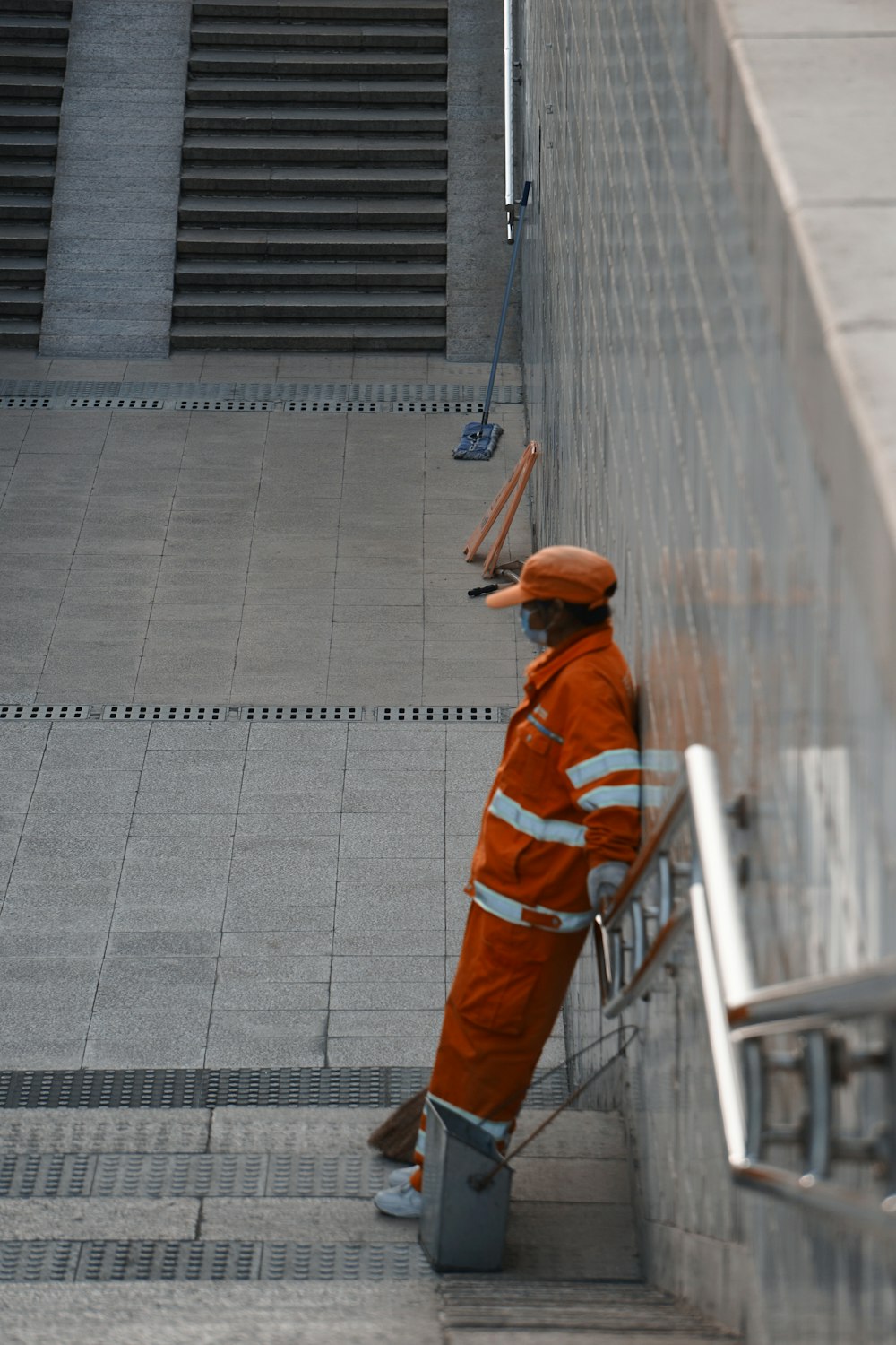 man in orange jacket walking on gray concrete pavement