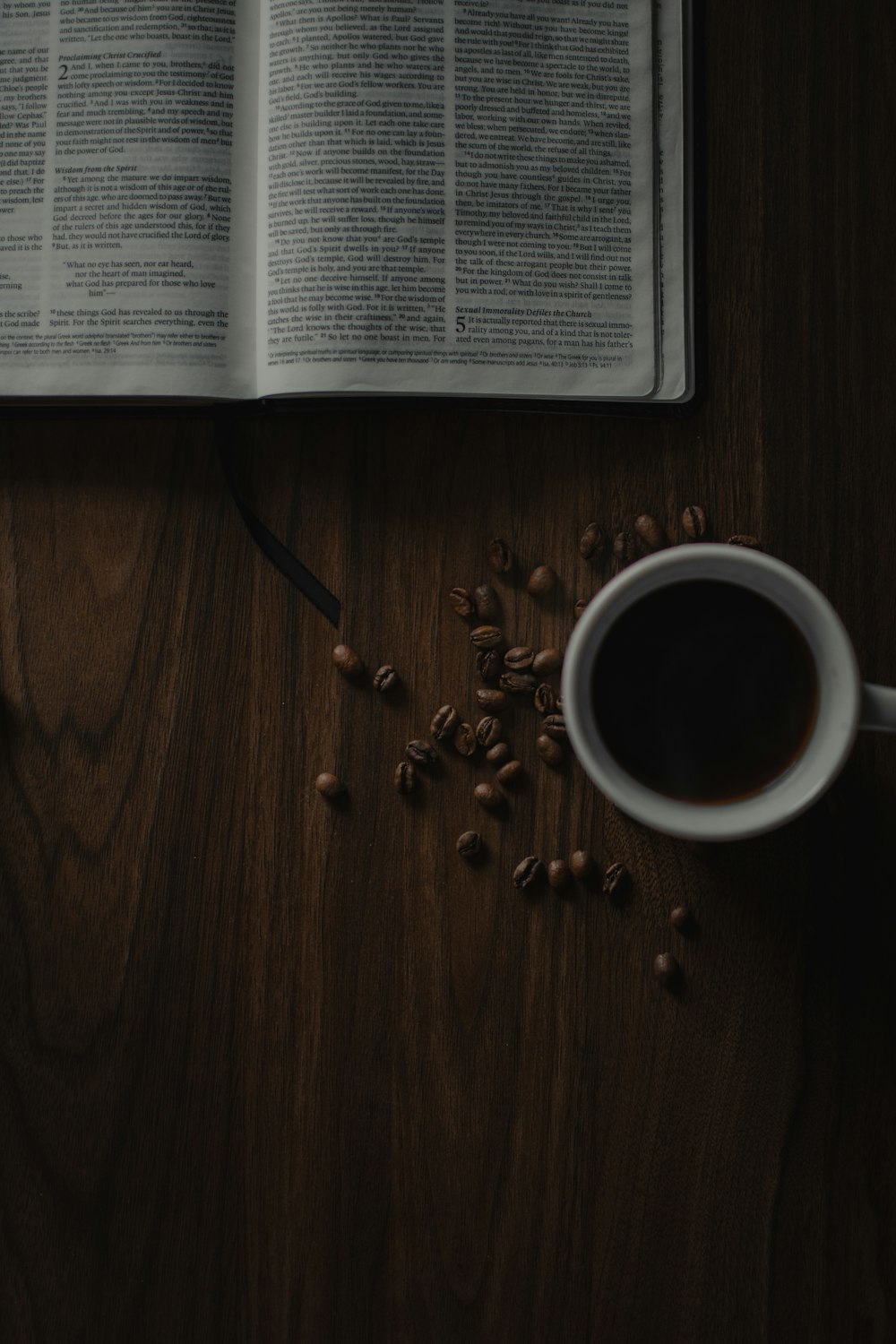 weiße Keramiktasse neben Buch auf braunem Holztisch