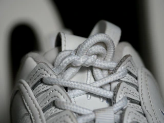 Close-up of hands lacing premium running shoes on a clean white background.
