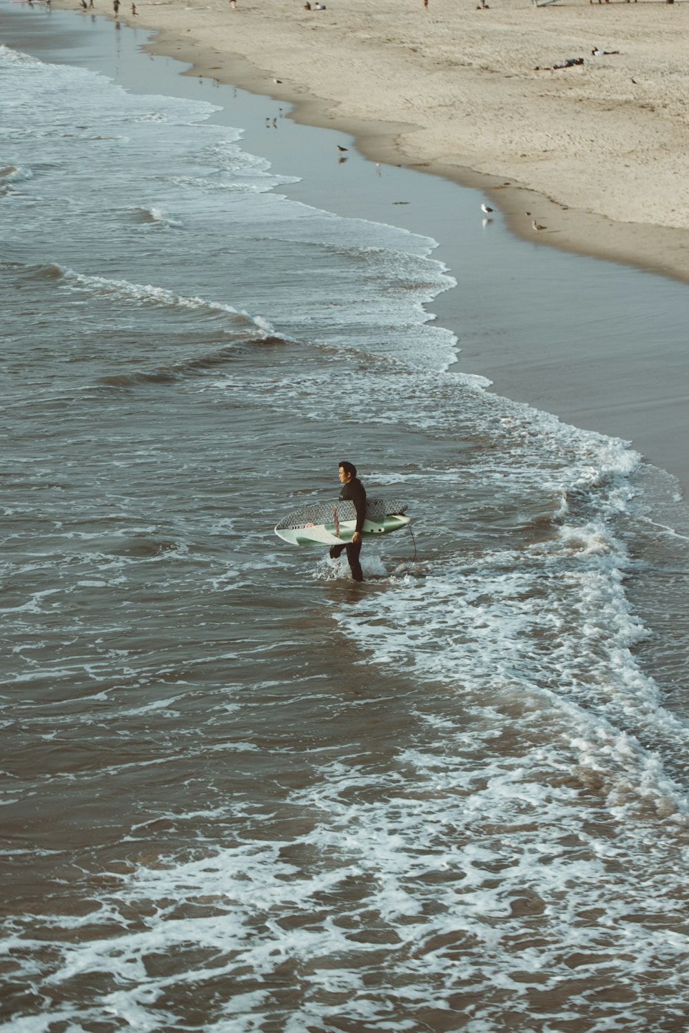 woman in white dress walking on beach during daytime