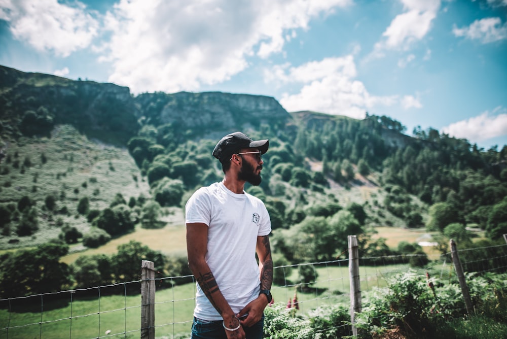 man in white crew neck t-shirt and red shorts standing on green grass field during