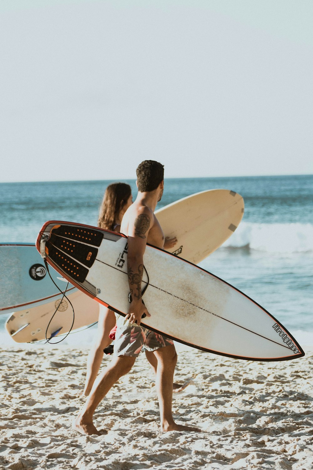 man holding white and red surfboard on beach during daytime