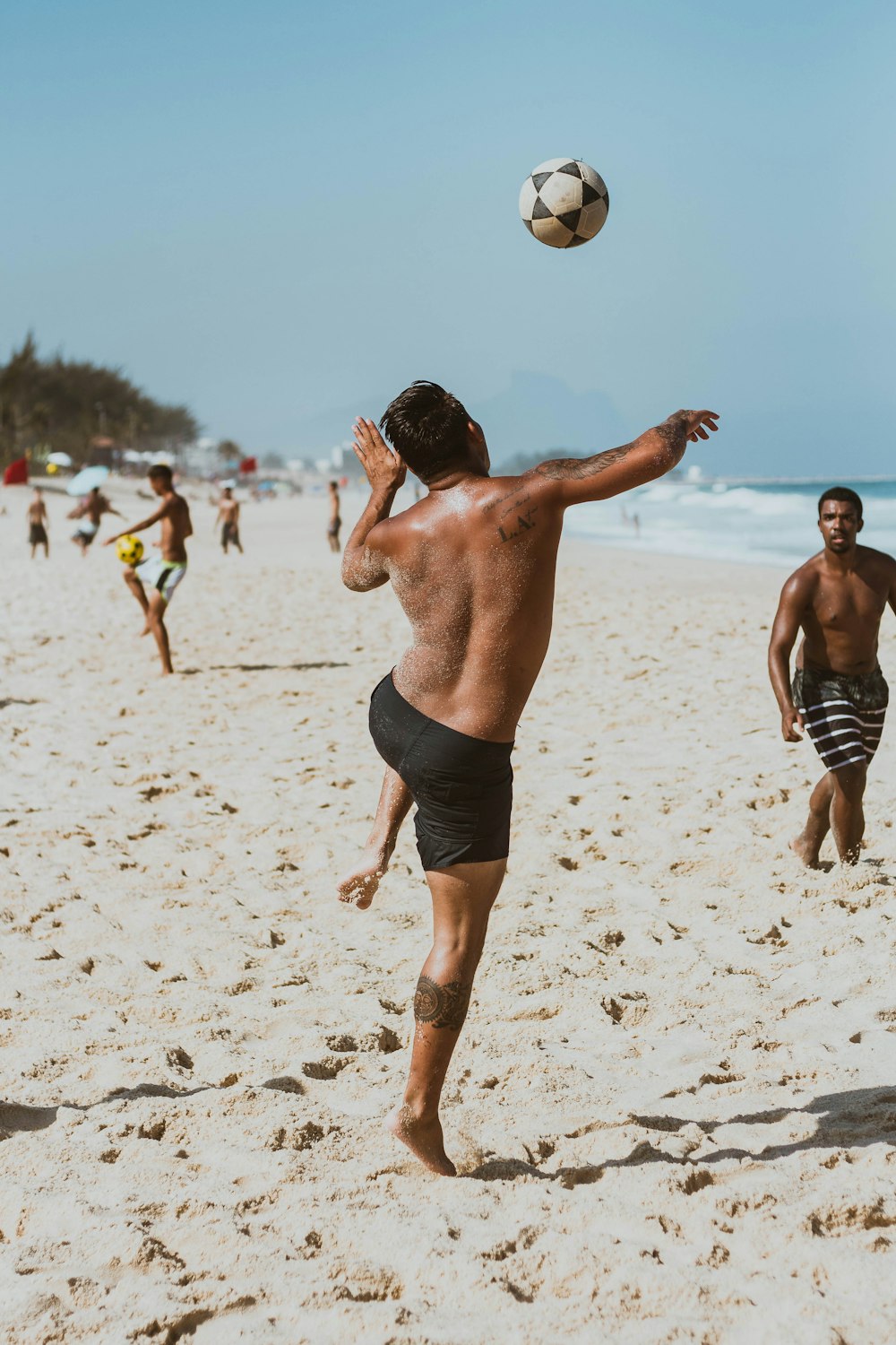 man in black shorts running on white sand during daytime