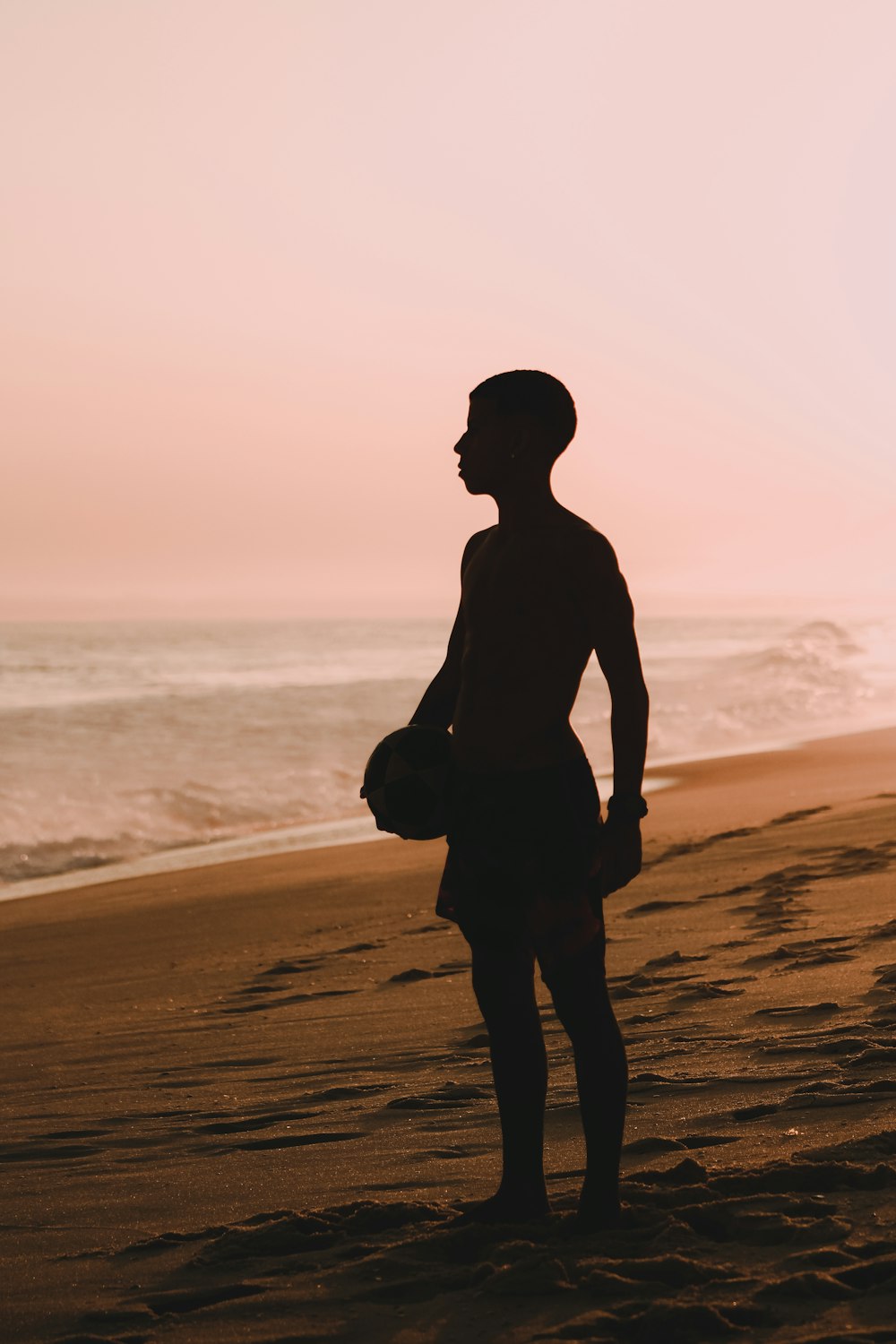 silhouette of man standing on beach during sunset