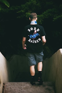 man in black crew neck t-shirt and blue shorts standing on stairs