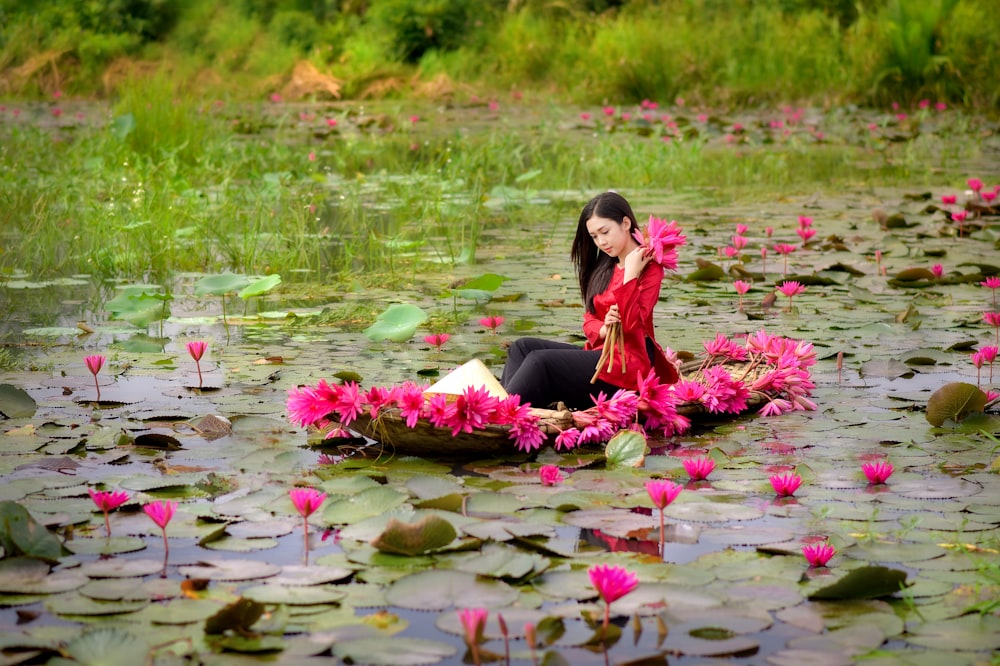 woman in black long sleeve shirt sitting on pink flower bed