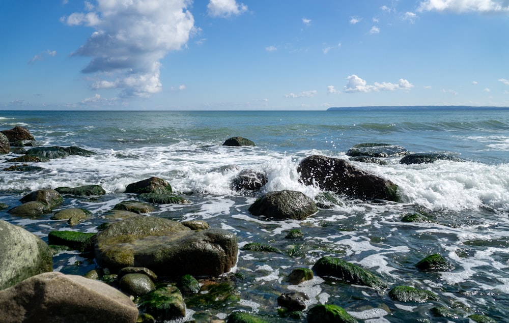 brown rocks on sea shore under blue sky and white clouds during daytime