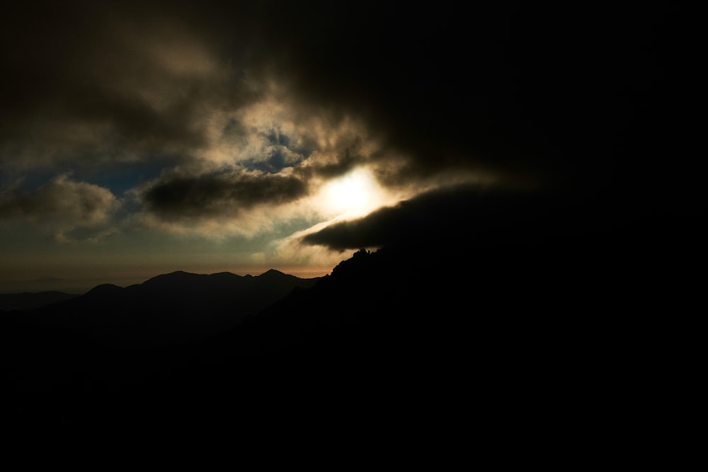 silhouette of mountain under cloudy sky during daytime