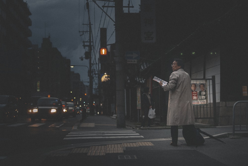 mulher no casaco branco em pé na faixa de pedestres durante o dia