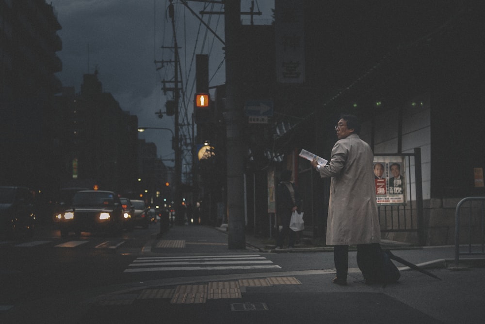 woman in white coat standing on pedestrian lane during daytime