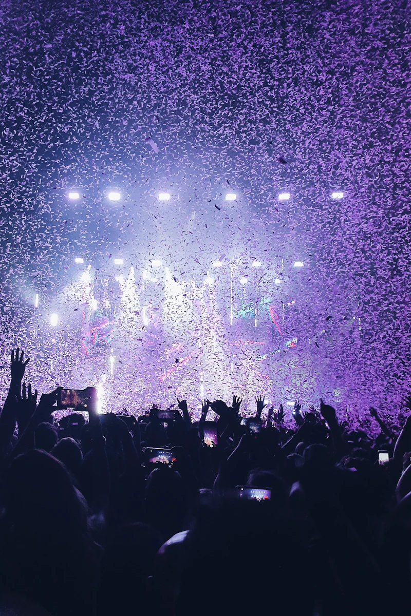 Confetti and bright stage lights above a jubilant crowd at a live concert