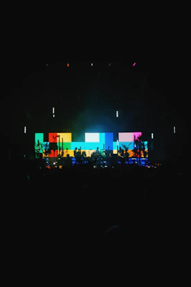 A vibrant event setup showcasing professional sound equipment, colorful lighting, and a large LED panel in use.