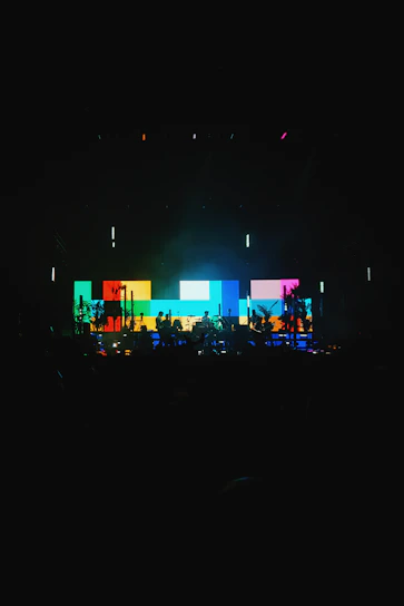 A vibrant audiovisual setup with screens and lighting at a live event.