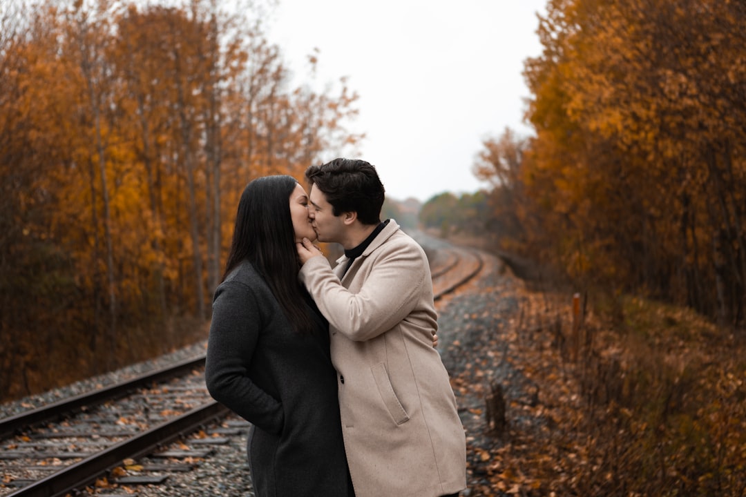 man and woman kissing on train rail during daytime