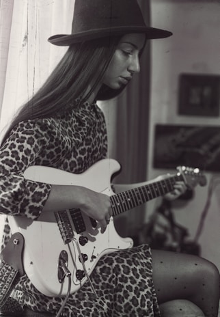Leo il leone che suona la chitarra sotto un tendone colorato.
