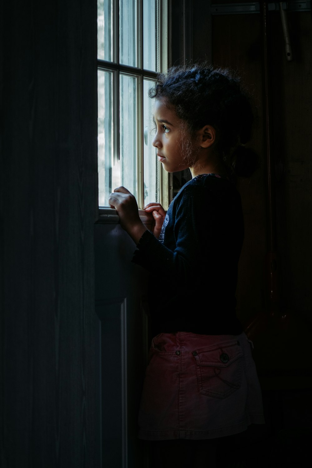 woman in black long sleeve shirt standing beside window