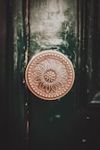 A vintage, ornate brass door knob with an intricate floral pattern adorns a dark green wooden door. The intricate details of the flower design and the aged patina of the metal offer a sense of history and craftsmanship.
