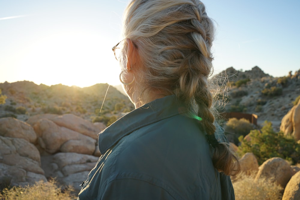 woman in black jacket standing on brown rock during daytime