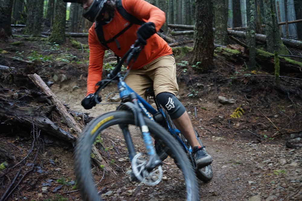 man in orange jacket and brown pants riding on black mountain bike