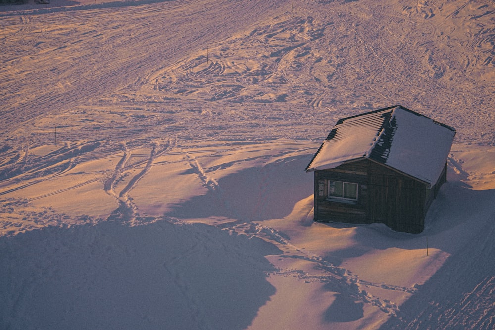 black wooden house on white snow covered field during daytime