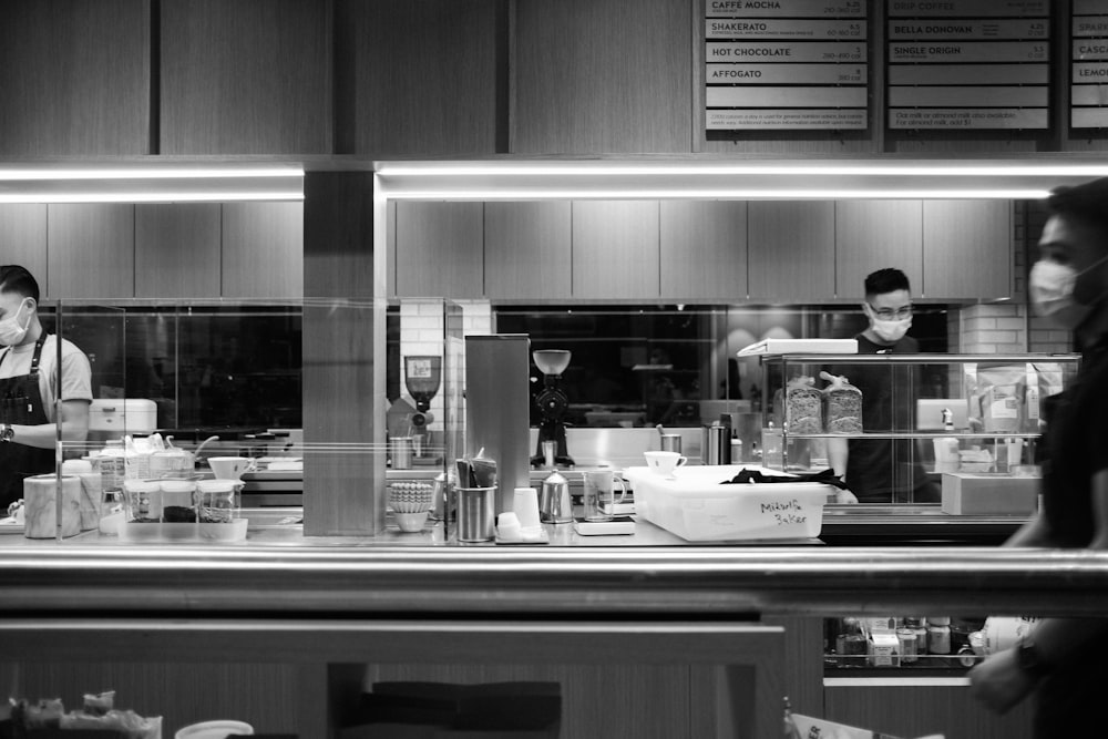 grayscale photo of man in kitchen