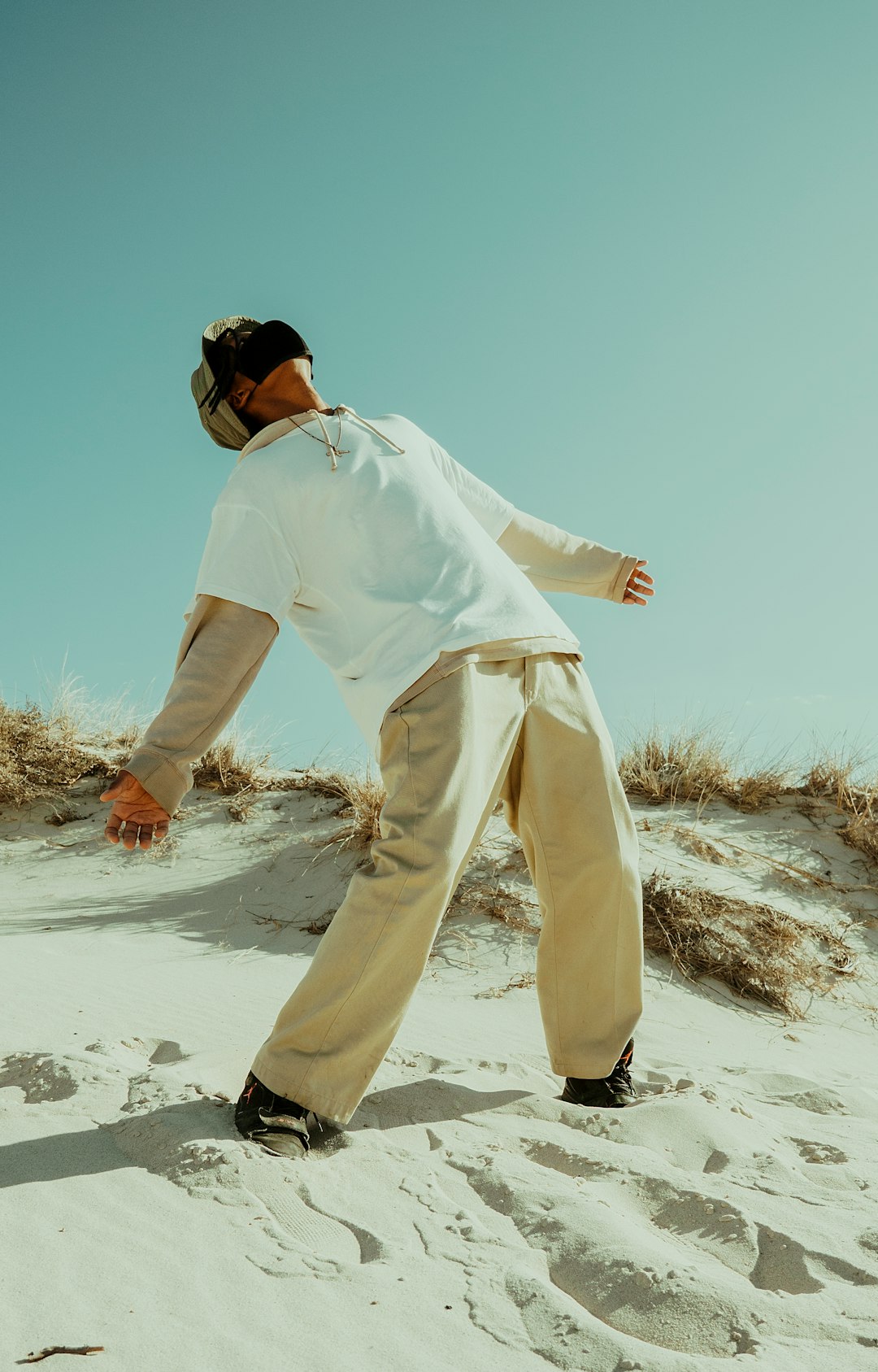 man in white long sleeve shirt and pants standing on white sand during daytime