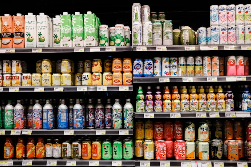 A cozy store shelf filled with various colorful beverage bottles under warm lighting.
