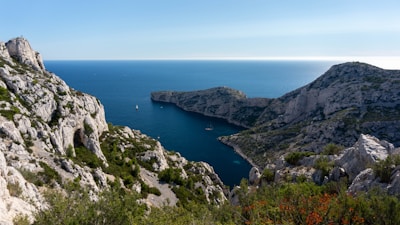 green and brown mountain beside blue sea under blue sky during daytime