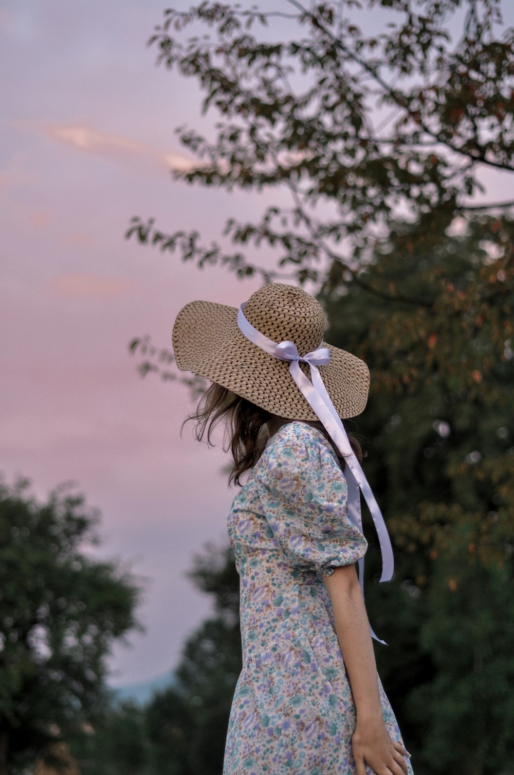 woman in white and blue floral dress wearing brown sun hat