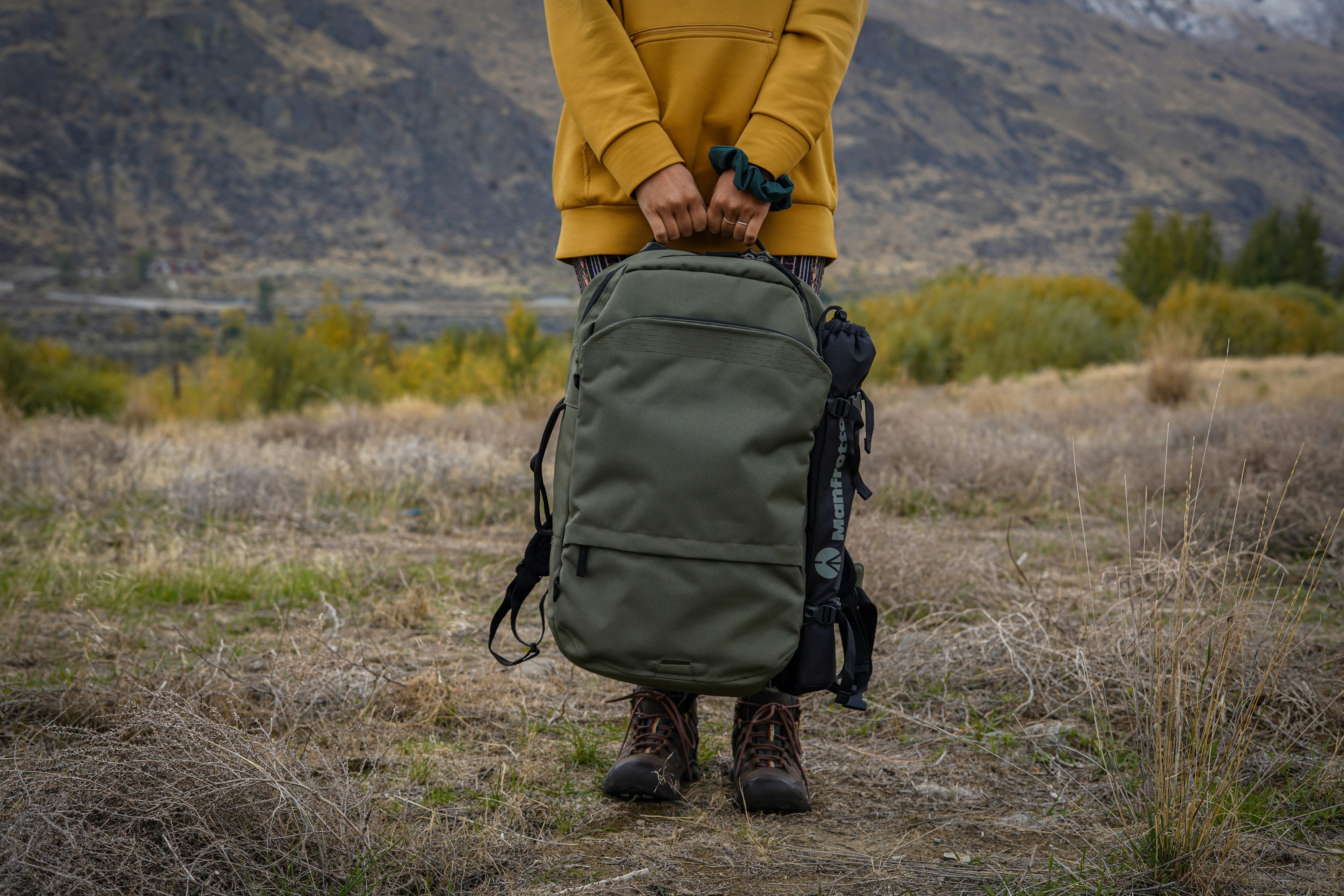 person in yellow jacket and black backpack walking on brown grass field during daytime