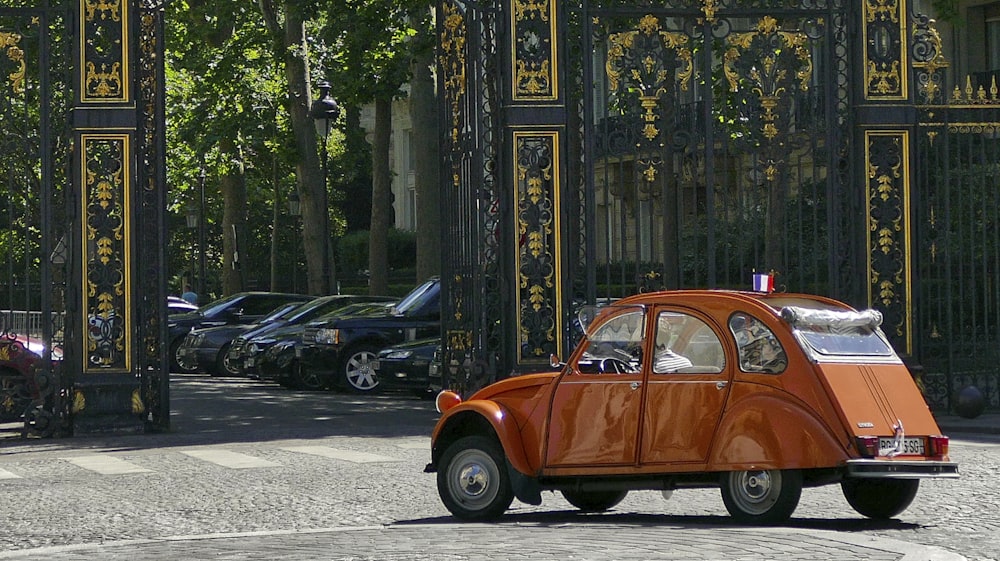 Volkswagen Beetle naranja estacionado en la acera durante el día