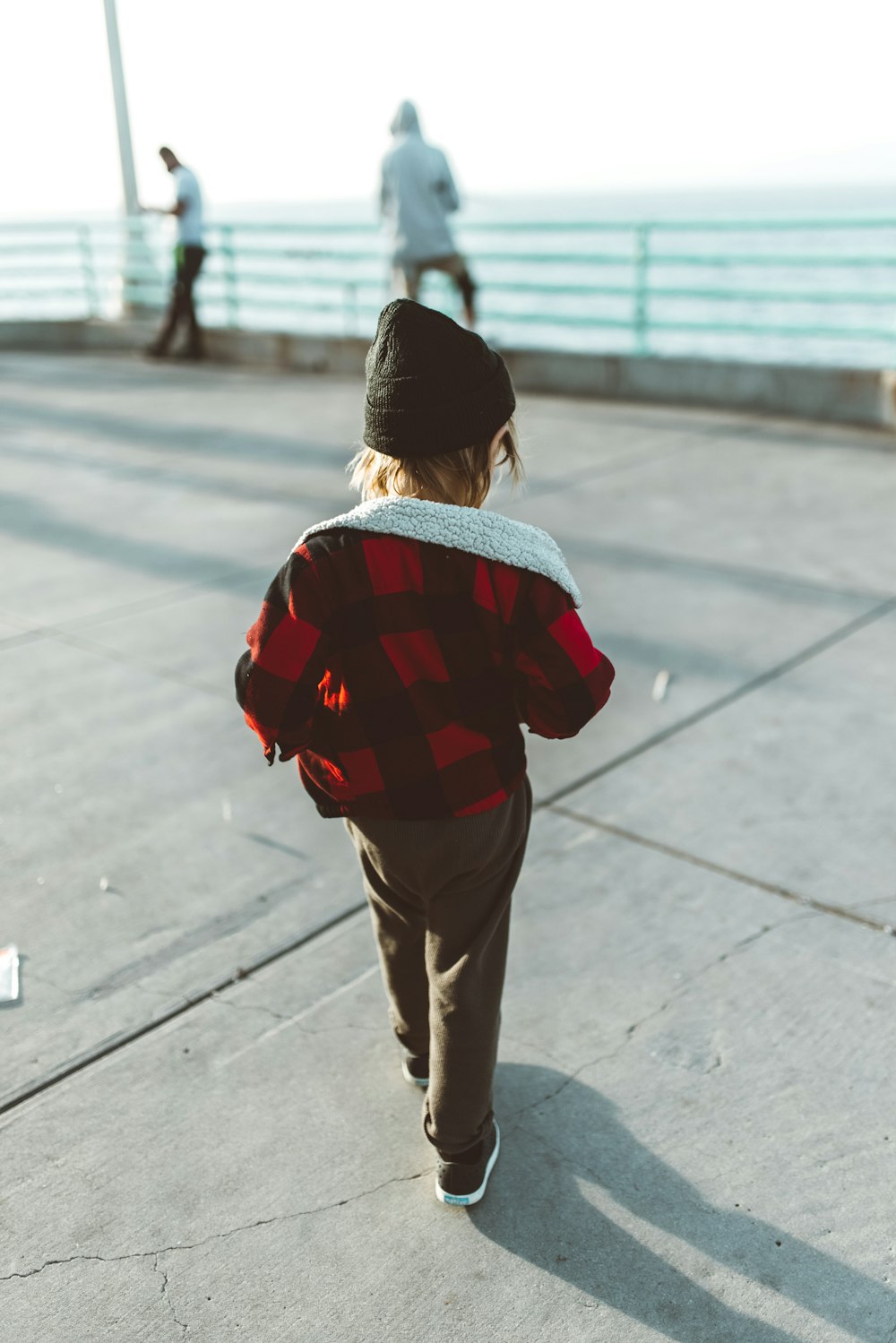 man in red and black plaid shirt and brown pants standing on gray concrete floor during