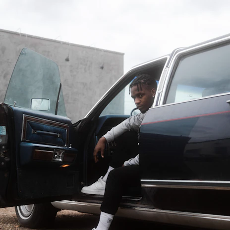 A professional driver opening the car door for a passenger in a city setting.