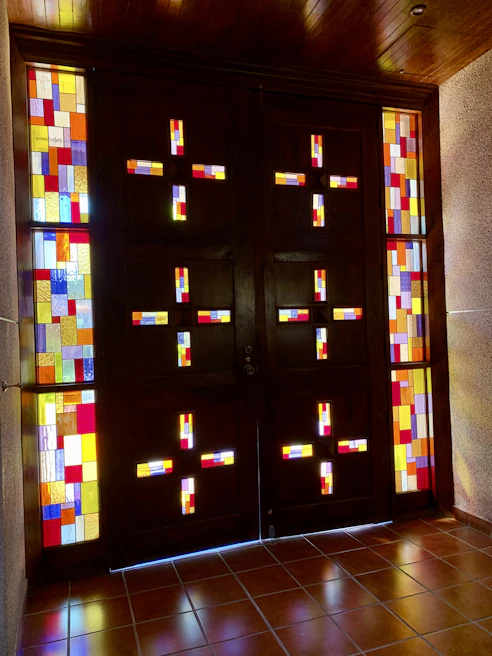 A modern wooden door with colorful stained glass panels glowing in natural sunlight