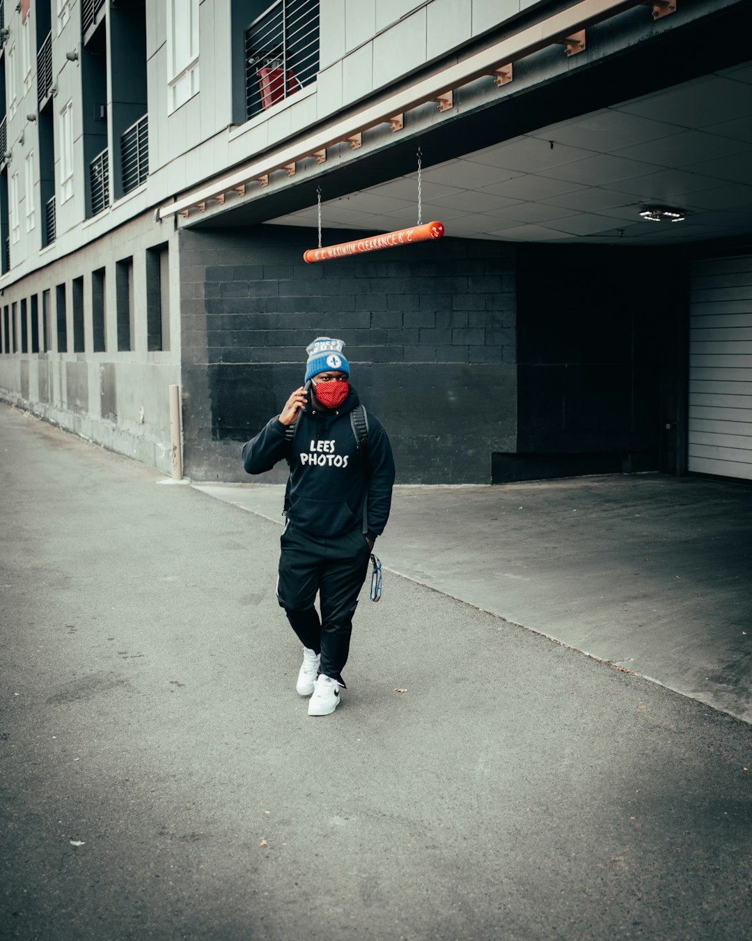 man in black jacket and black pants wearing black helmet walking on gray concrete floor