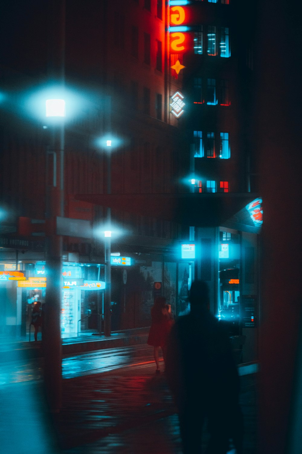 man in black coat walking on sidewalk during night time