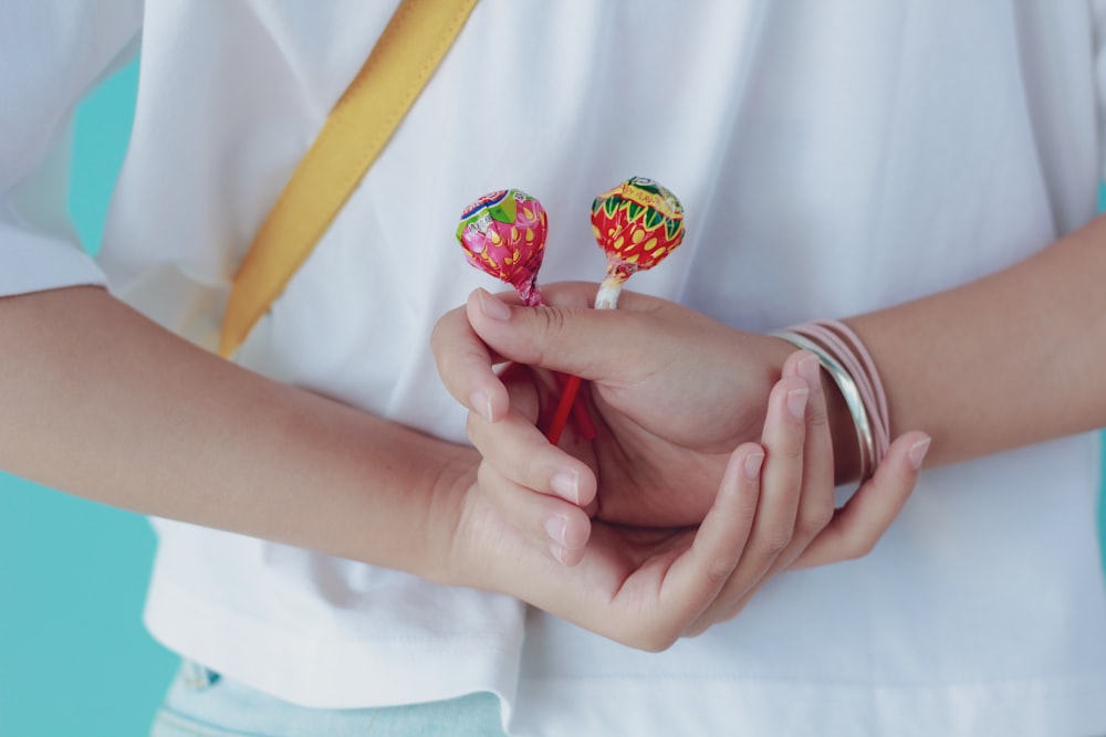 person holding red and yellow lollipop