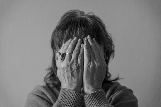 grayscale photo of woman covering face with her hands