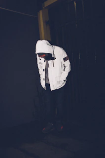 Detail shot of a sleeve patch with dripping paint effect on a dark hoodie under moody street lighting.