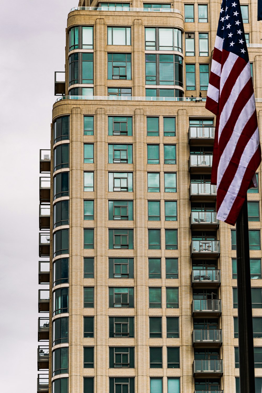 us flag on pole near brown concrete building during daytime