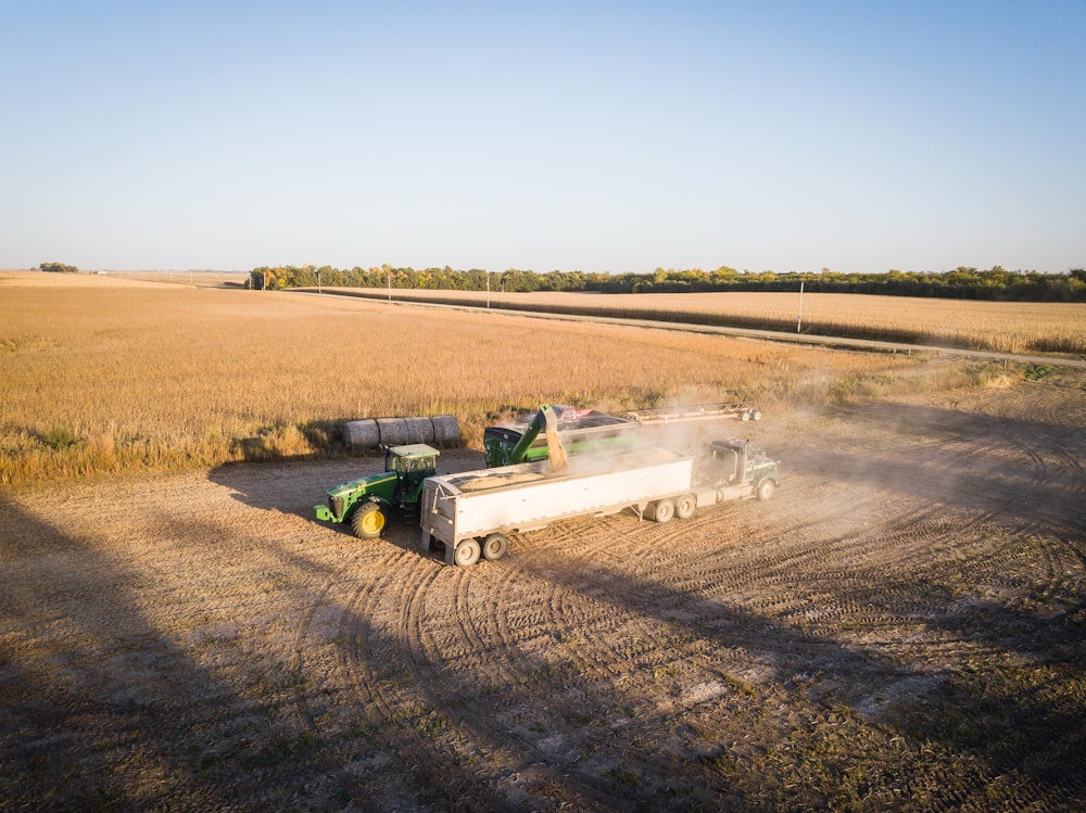 green and white tractor on brown field during daytime