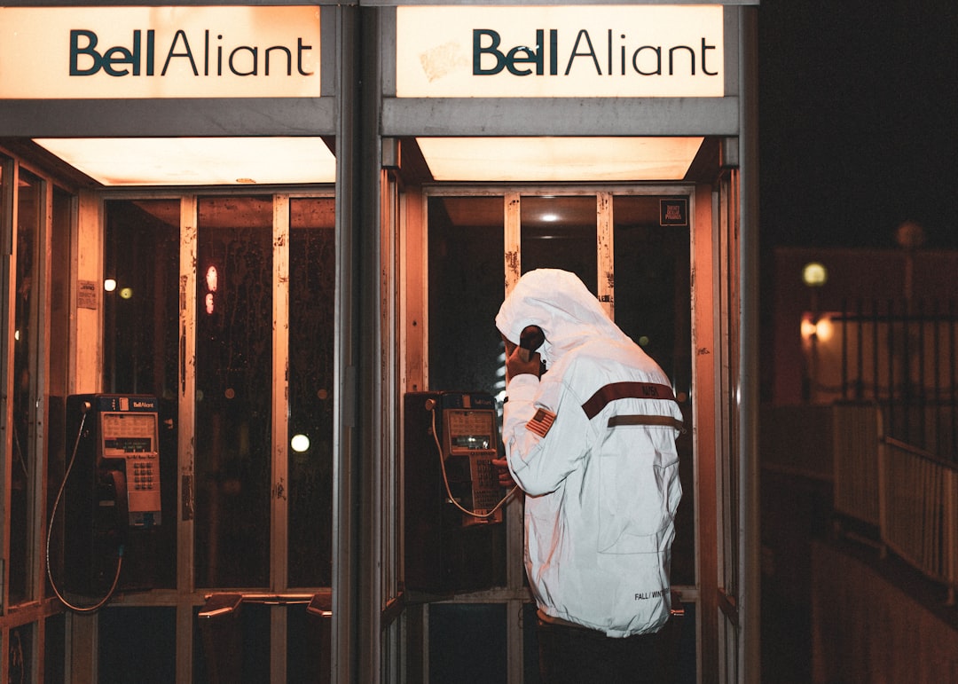 man in white and blue jacket standing in front of brown wooden door